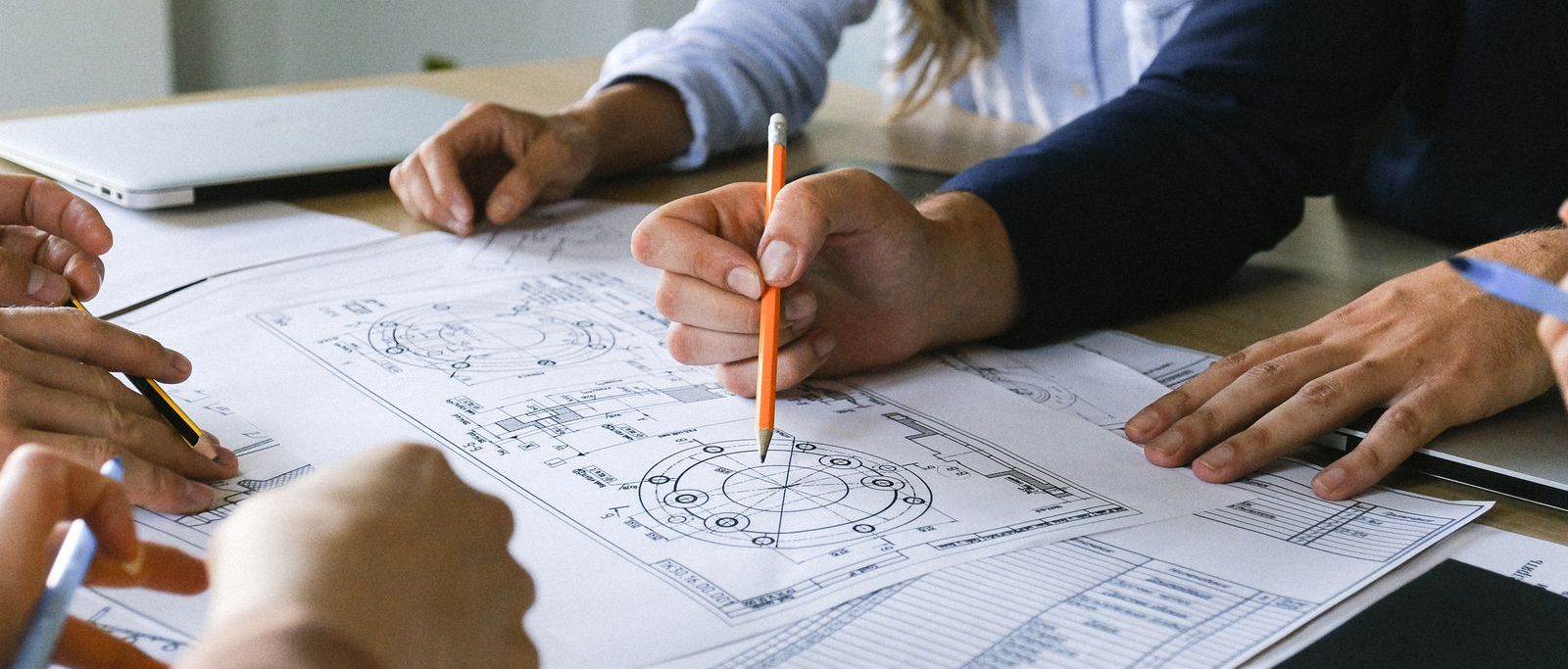 Equipe debruçada sobre plantas e documentos, estruturando um novo projeto de negócio
